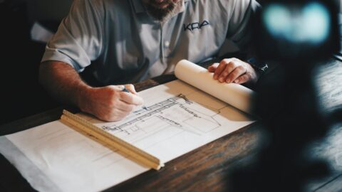 Construction professional reviewing building plans at a project site, illustrating capital project oversight