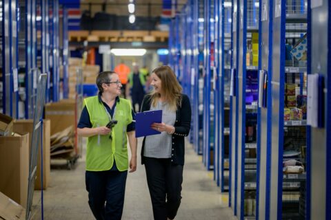 Warehouse colleagues reviewing inventory records and stock on shelves