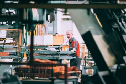 Factory worker operating industrial machinery as part of product quality and warranty risk management