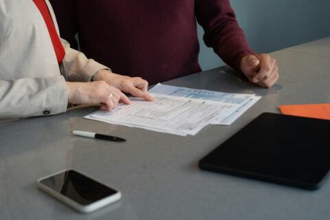 Two finance professionals reviewing paperwork at a conference table, illustrating supplier master data and payment control reviews.